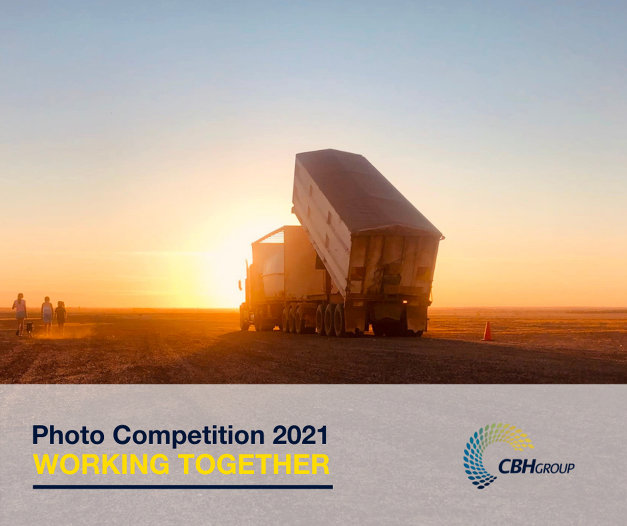 A truck tipping up its trailer in a paddock at sunset