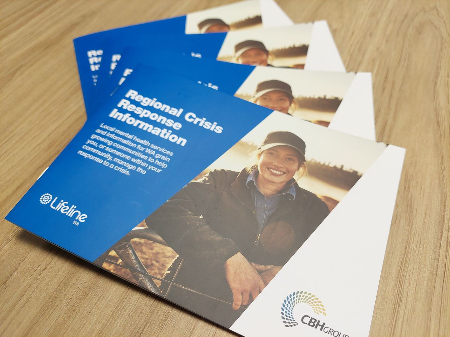 Four booklets with blue covers spread across a wooden table