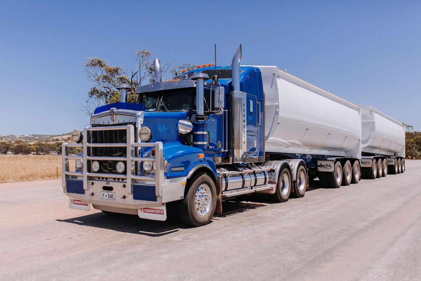 A large blue truck parked on a gravel road
