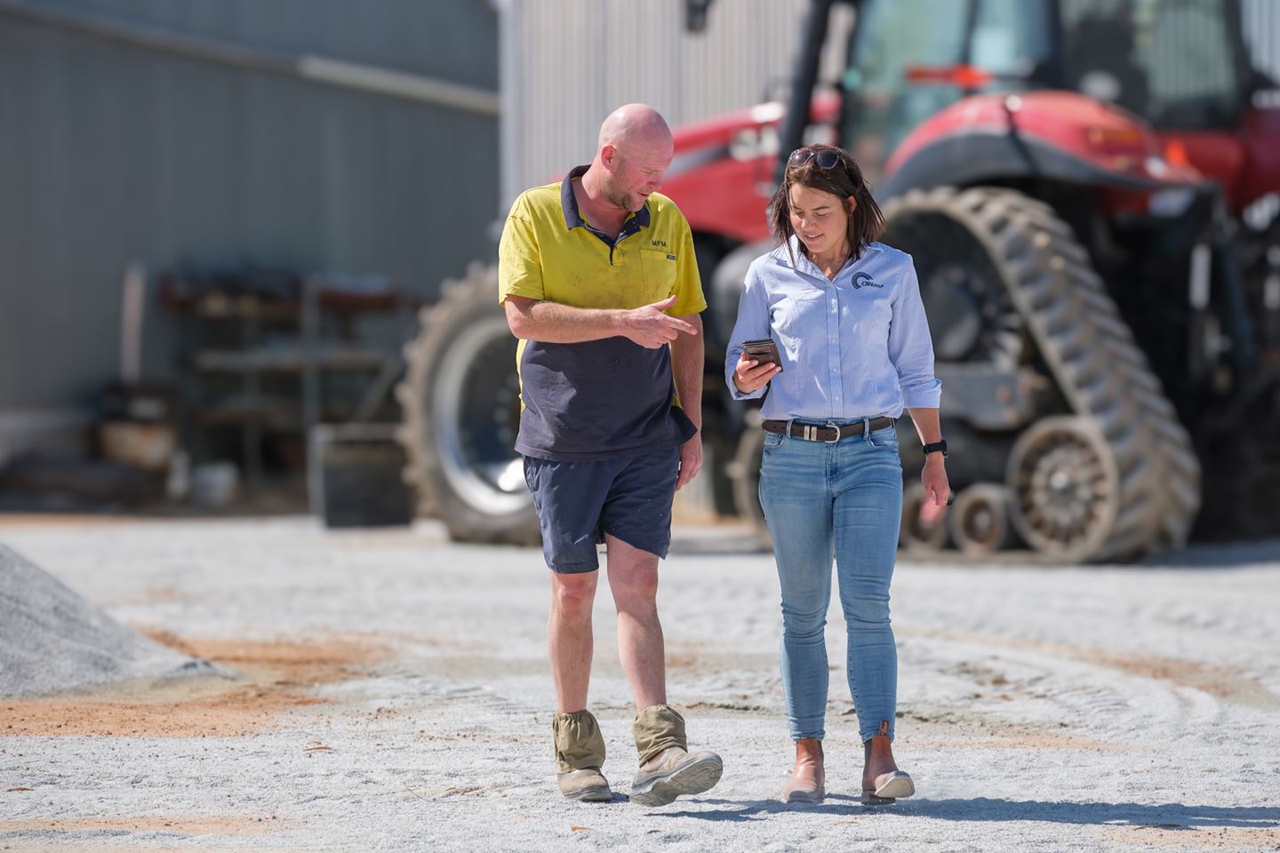 Two men in blue shirts standing in paddock inspecting crop